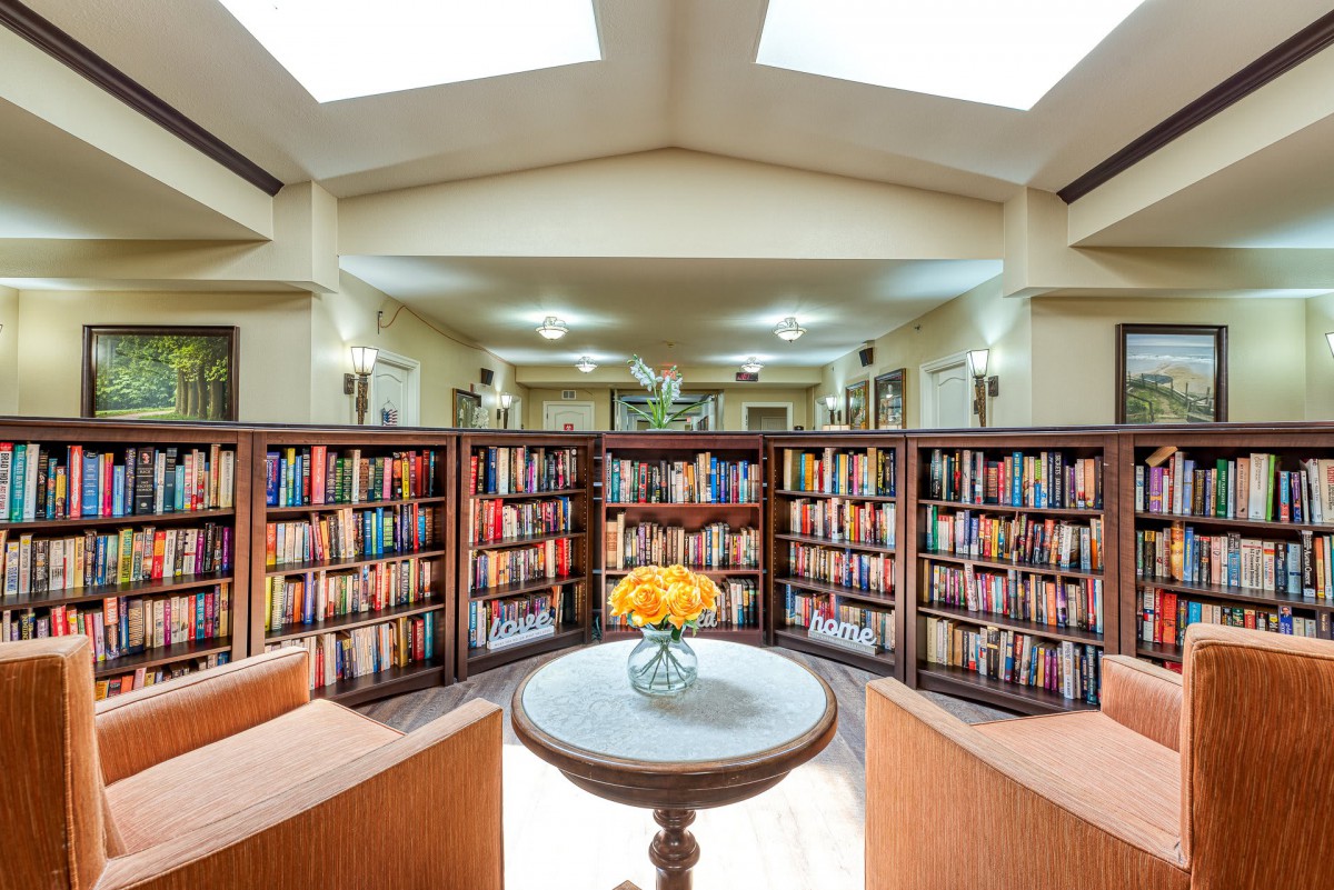A cozy library interior with bookshelves lined with colorful books and a skylight above.