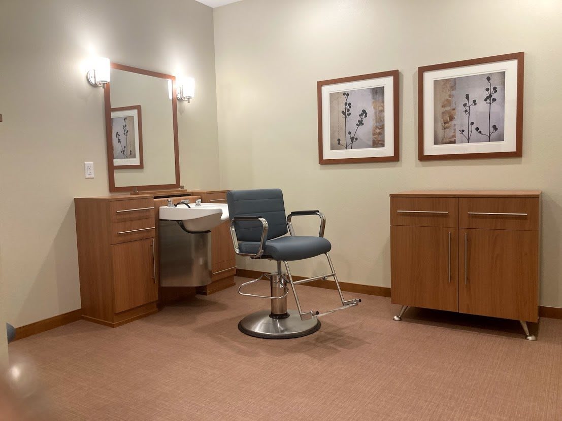 A salon setup with a barber chair, sink, and mirrors.