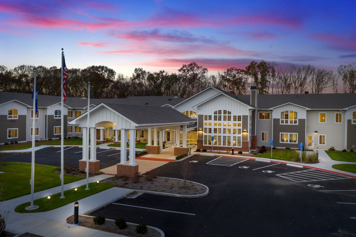 A building with an entrance and parking lot at sunset.