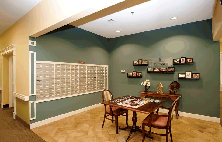 A cozy mailroom with a table, chairs, and wall-mounted mailboxes.