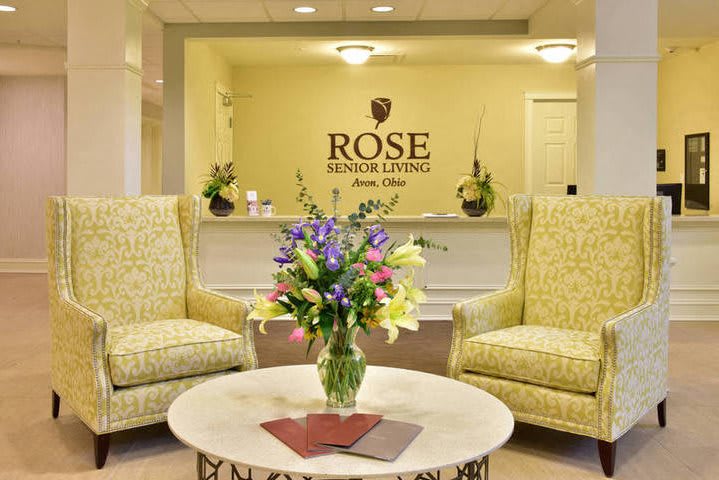 A cozy lobby area featuring two upholstered chairs, a floral arrangement on a round table, and a welcoming ambiance.