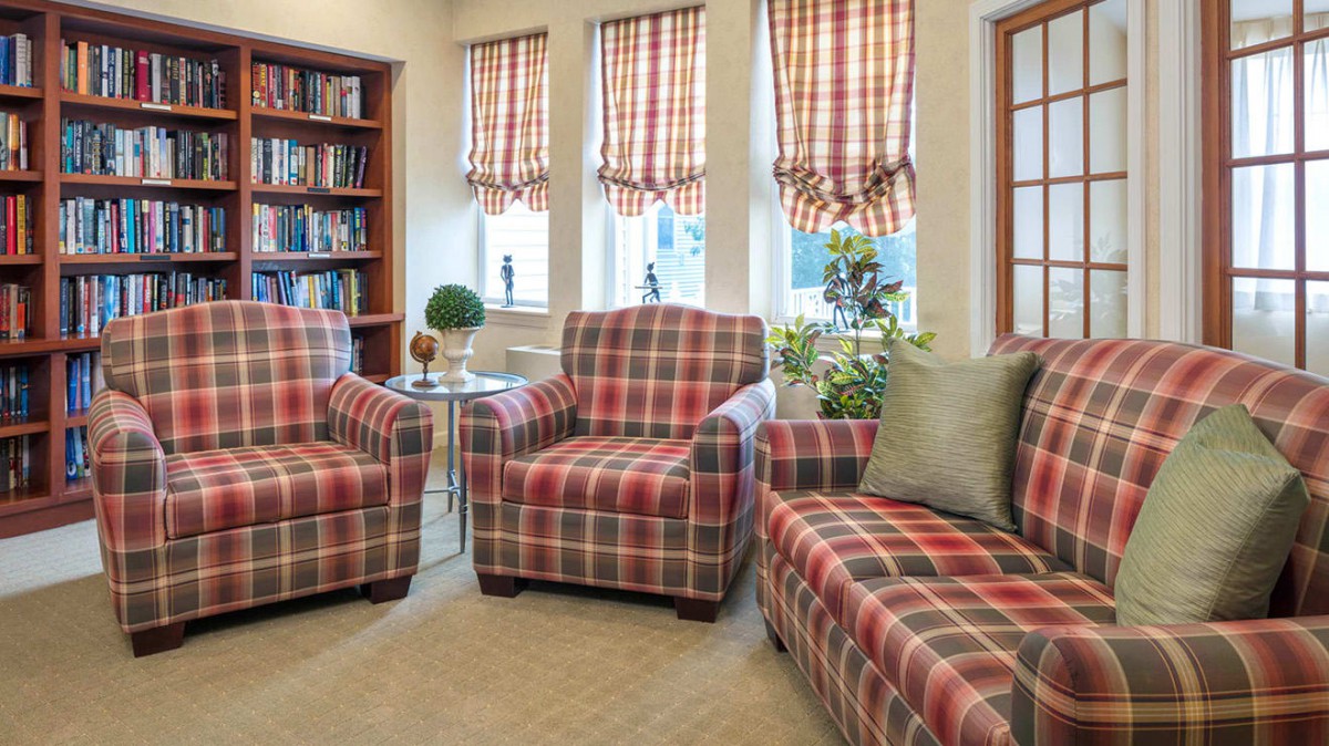 A cozy living room with plaid-patterned chairs and a bookshelf.