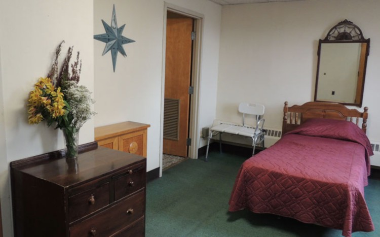 A cozy bedroom with a bed, dresser, and decorative wall elements.