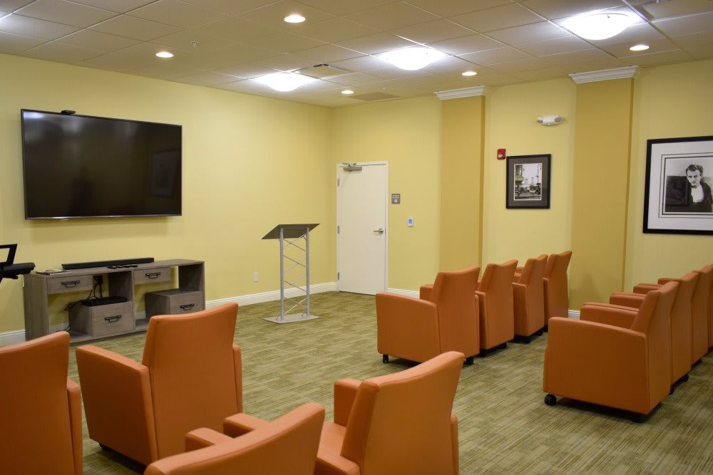 A small conference room setup with comfortable chairs, a television, and a podium.