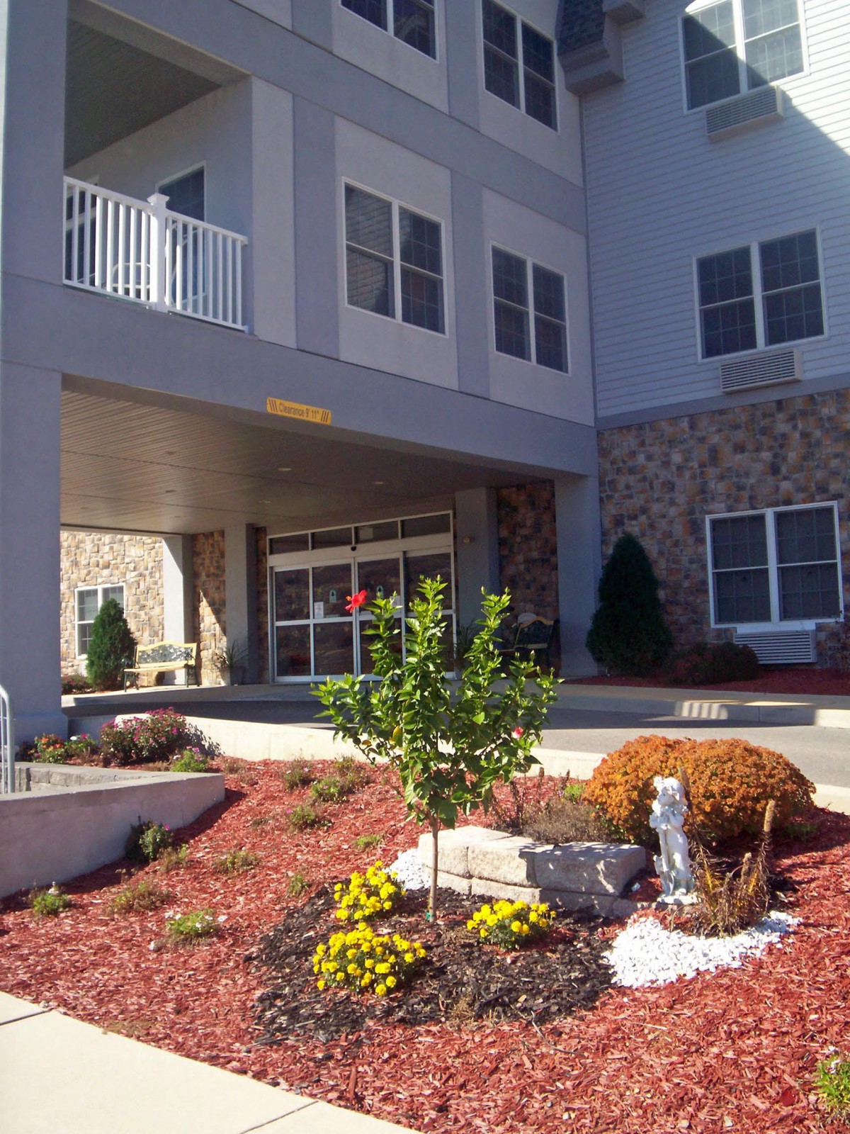 A landscaped entrance of a modern building with stone accents and well-maintained plants.