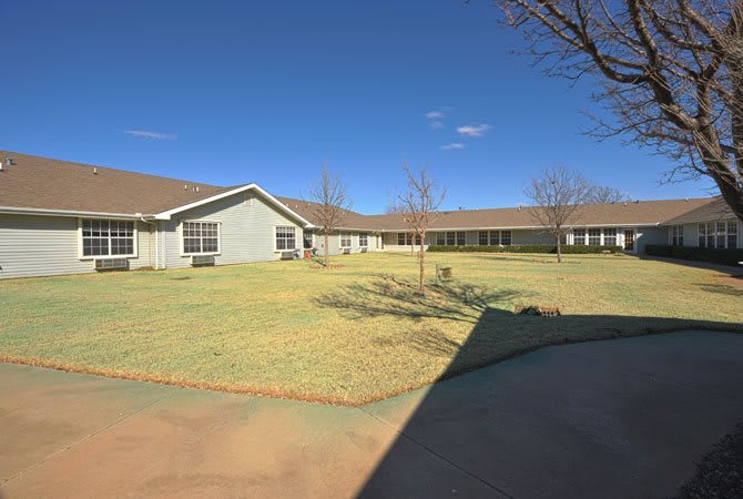 A view of a single-story building with a large lawn and clear blue sky.
