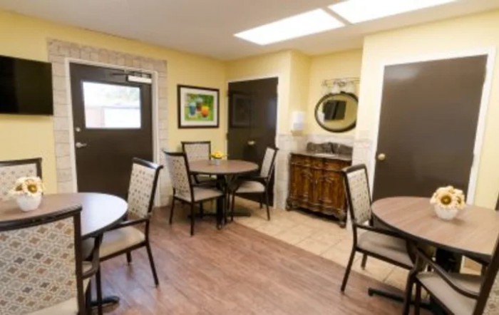 A cozy dining area with round tables and chairs, decorated with artwork and a mirror.