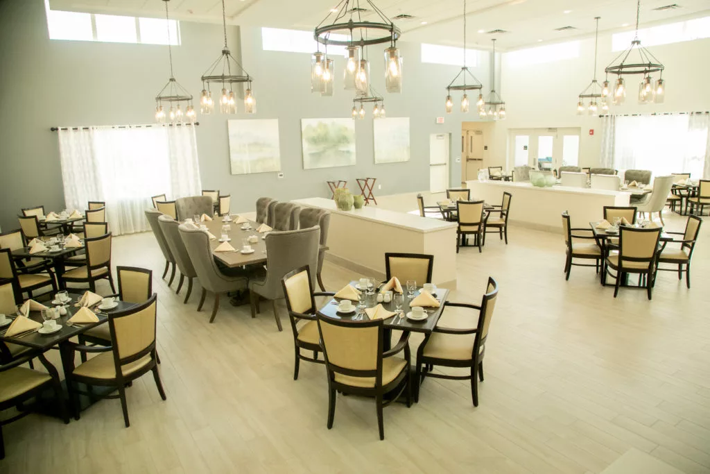 A spacious and elegantly designed dining area with multiple tables, comfortable seating, and decorative chandeliers.