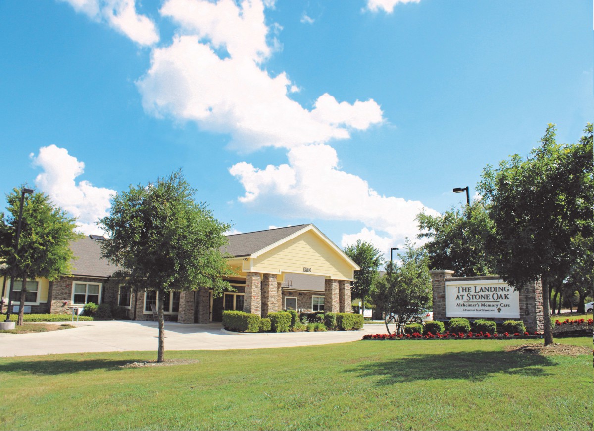A building with a lawn and a sign under a bright blue sky with clouds.
