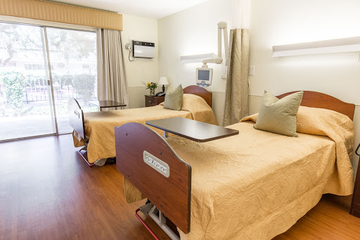 A well-lit and comfortable hospital patient room featuring two adjustable beds.