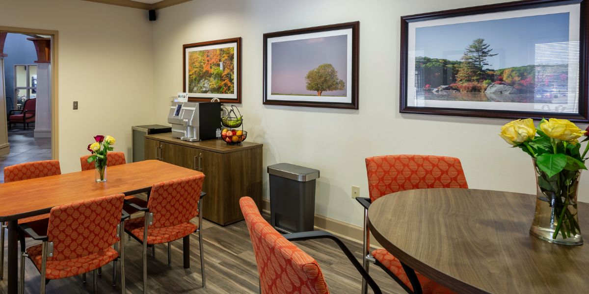 A cozy waiting area with orange chairs, a coffee station, and framed artwork on the walls.