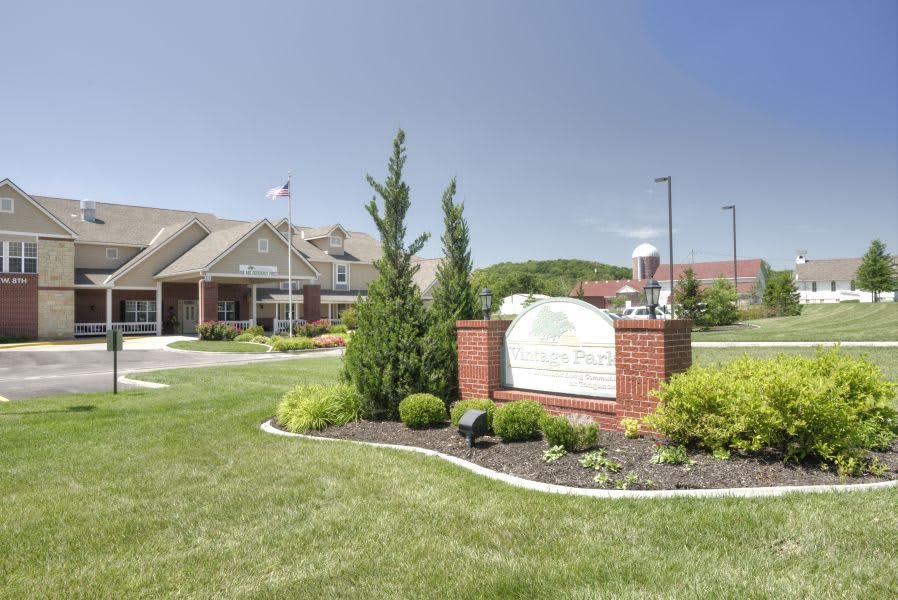 A landscaped area featuring a building and a sign surrounded by greenery.