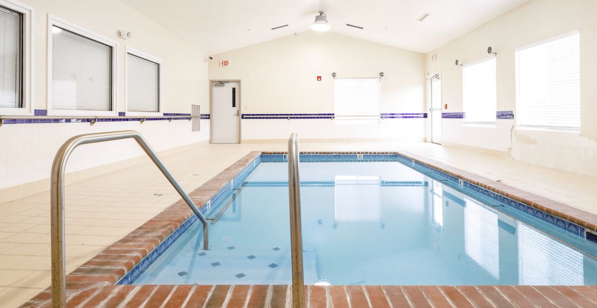 An indoor swimming pool with clear water and brick trim, ideal for exercise and relaxation.