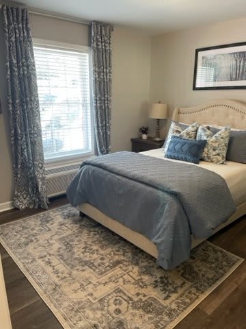 A cozy bedroom with a neatly made bed, decorative pillows, and elegant curtains.
