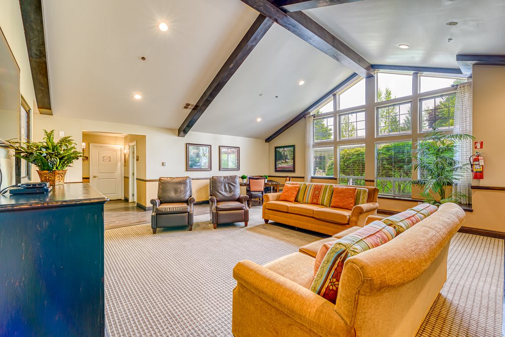 A spacious living room with large windows, featuring comfortable sofas and chairs.