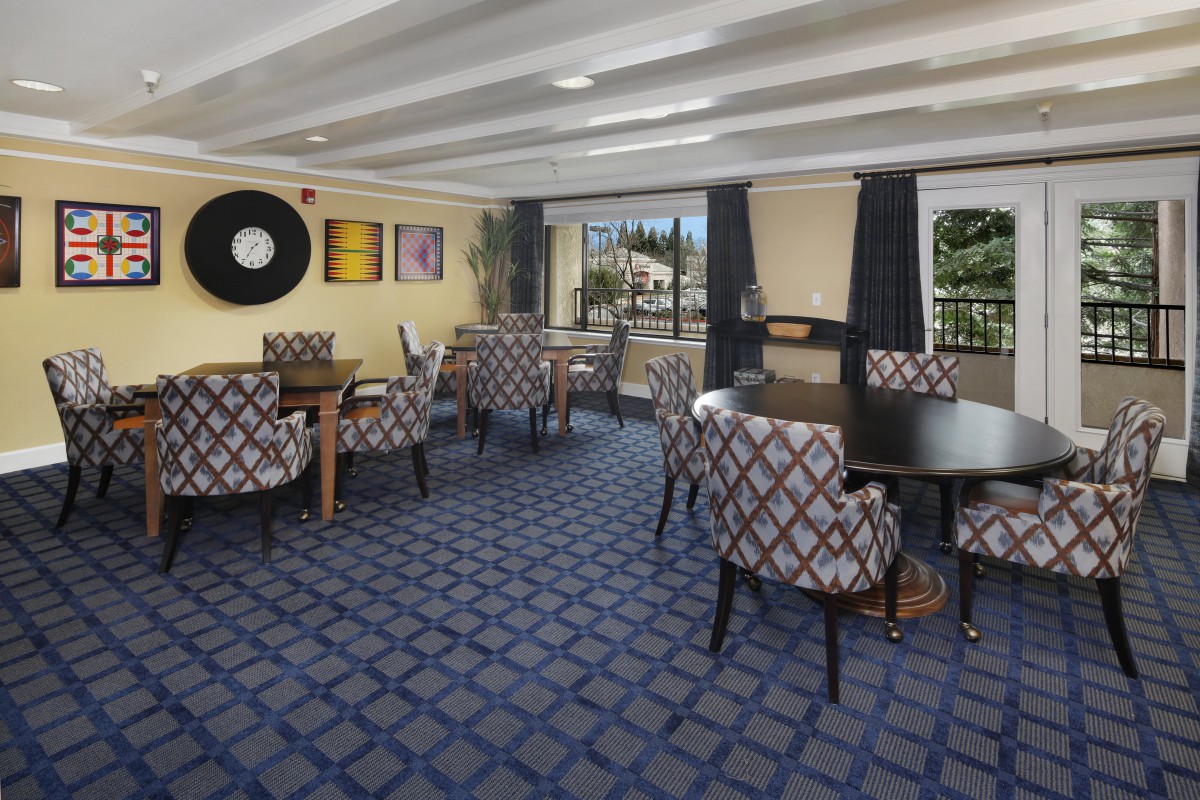 A cozy dining area with patterned chairs and tables, featuring modern decor and carpet.