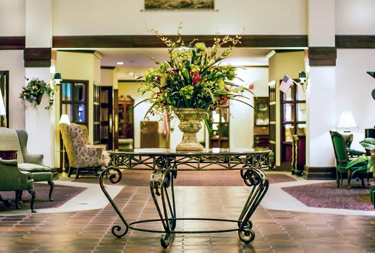 A luxurious hotel lobby featuring a decorative table with an elegant flower arrangement.