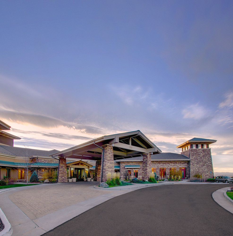 A modern building with a spacious driveway under a cloudy sky.