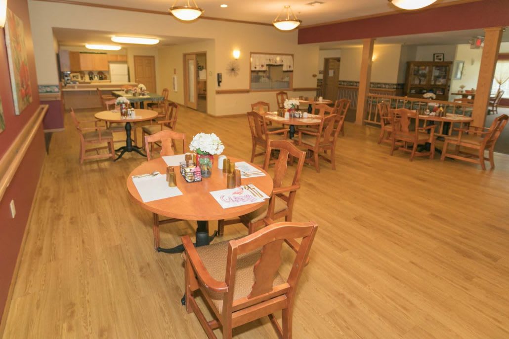 An empty dining area with wooden tables and chairs, featuring soft lighting and a cozy atmosphere.