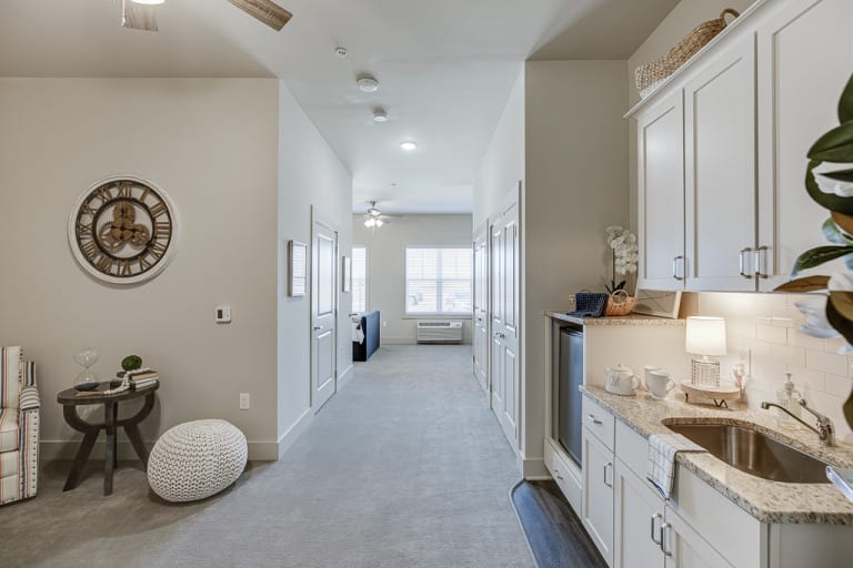 A modern hallway with a kitchenette leading to a bright living room.