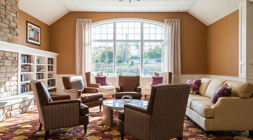 A cozy living room with large windows, stylish chairs, and a central table.