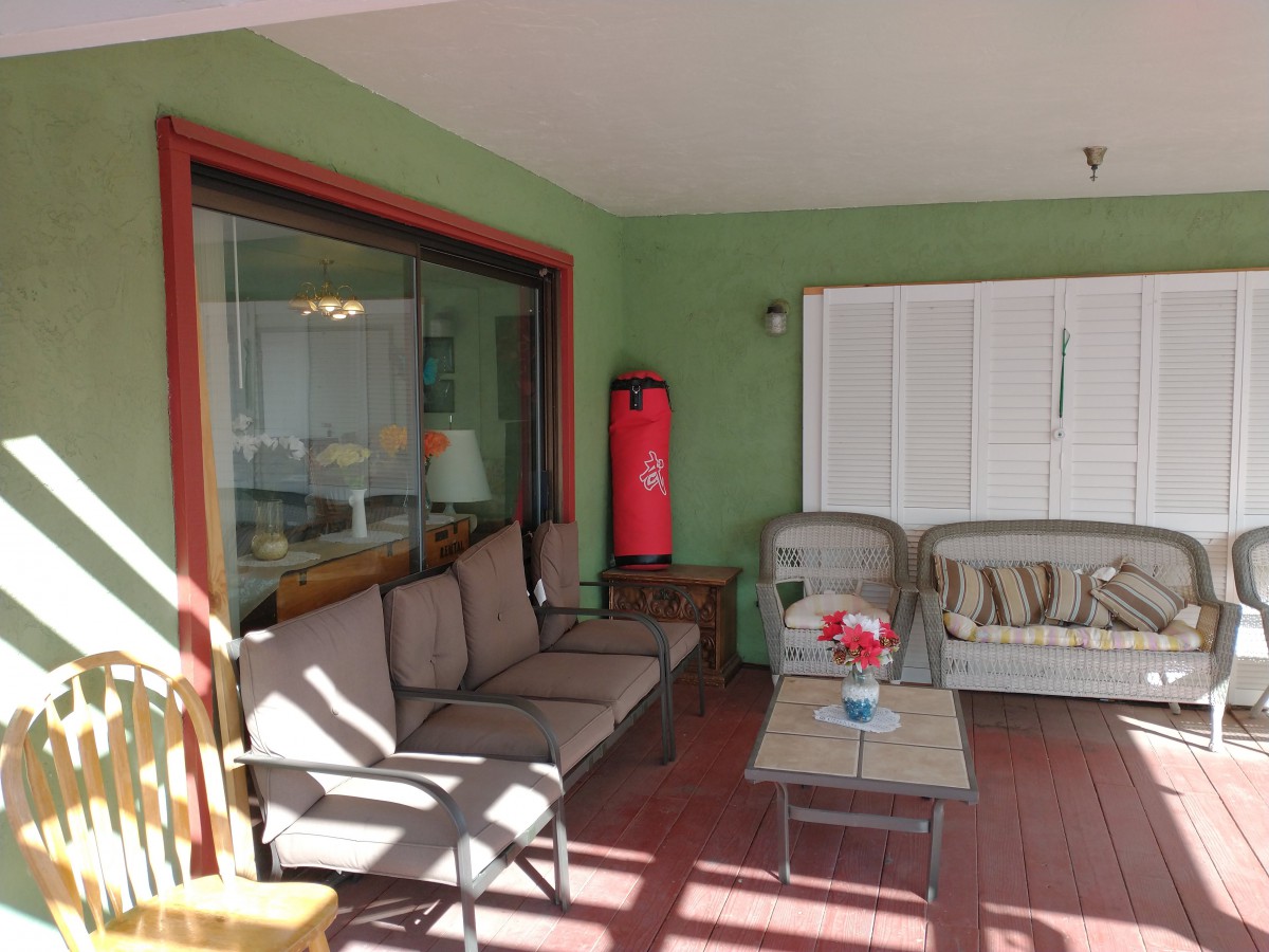 A cozy patio area with comfortable seating and a coffee table, bathed in sunlight.