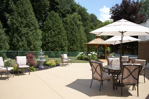 A spacious patio area with outdoor furniture, umbrellas, a gazebo, and lush greenery.