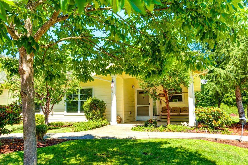 A charming house with a lush green front yard and mature trees.
