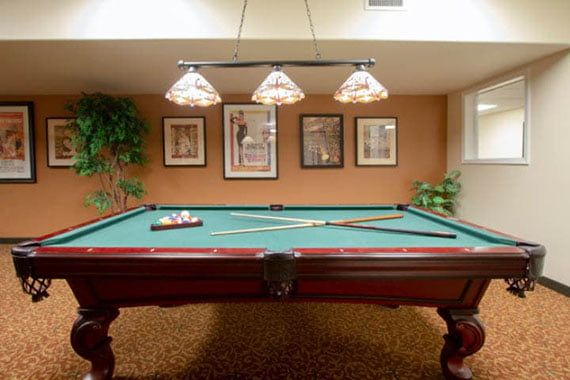 A cozy game room featuring a pool table under stylish lighting.