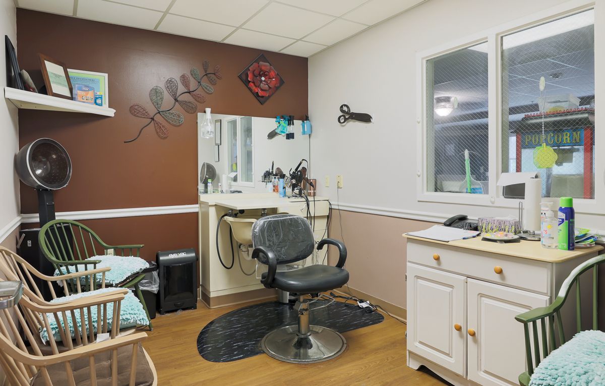 A cozy hair salon interior with a styling chair and mirrors, adorned with decorative elements on the walls.
