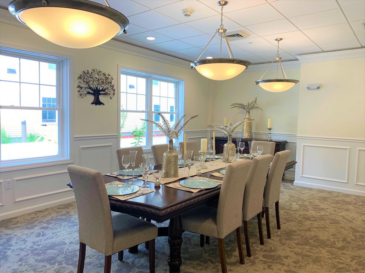 A well-appointed dining room with a large table set for guests, featuring elegant lighting and decor.