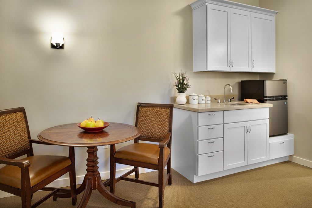A cozy dining area with a small round table, chairs, and a kitchenette.