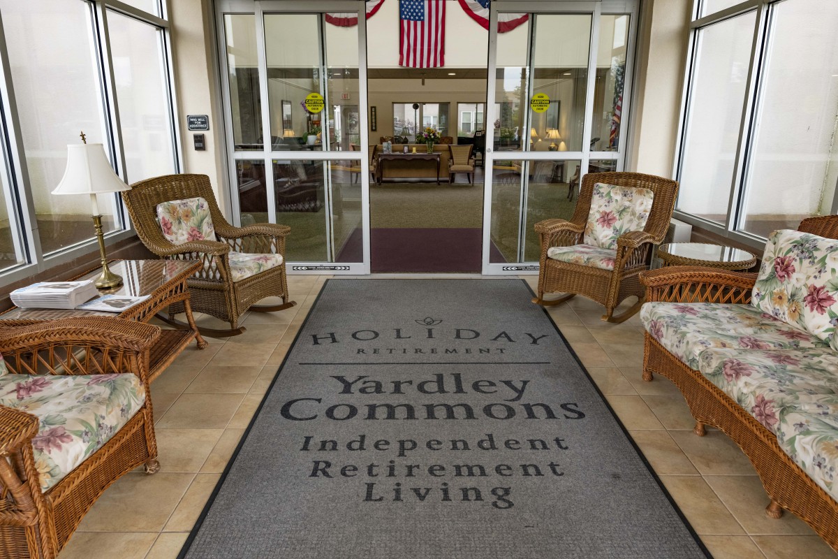Entrance to Yardley Commons Independent Retirement Living with seating arrangements and a welcome mat.
