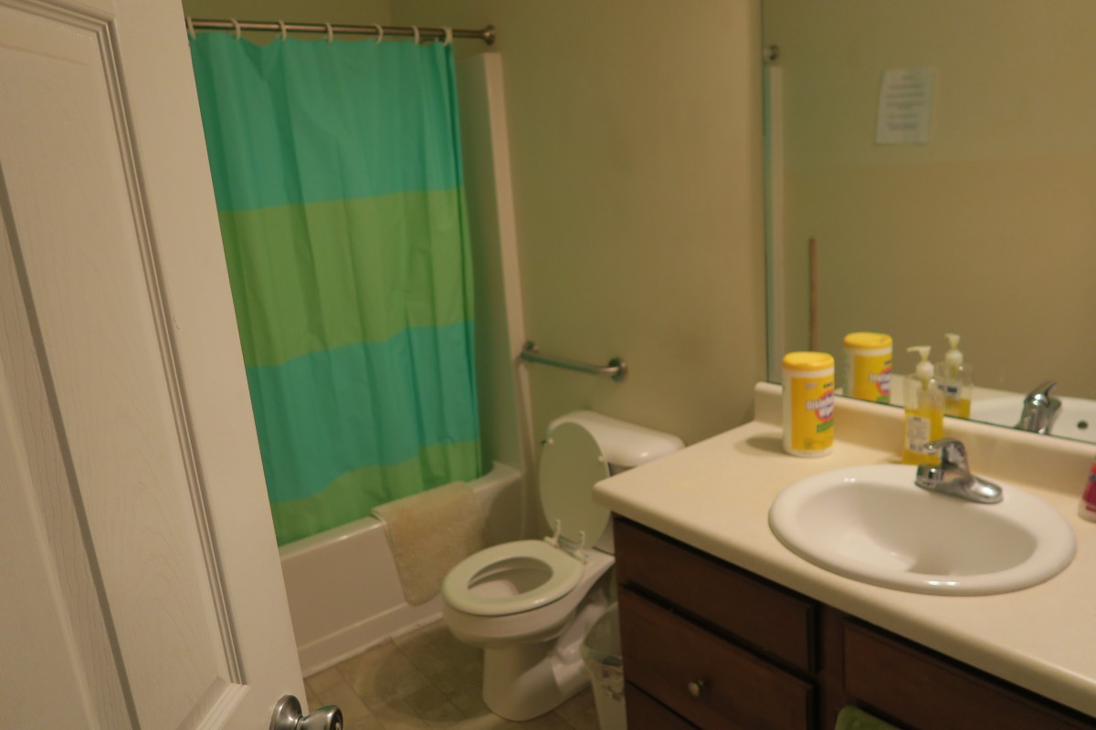 A compact bathroom with a colorful shower curtain and neatly arranged toiletries on the counter.