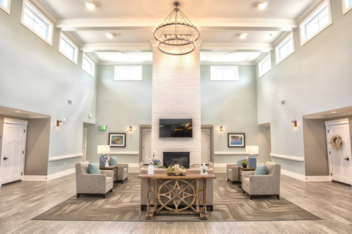 A modern and elegant lobby with plush seating areas, a central fireplace, and a large chandelier overhead.