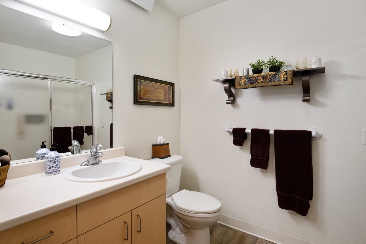 A neatly organized bathroom with a sink, toilet, and decorative shelving.