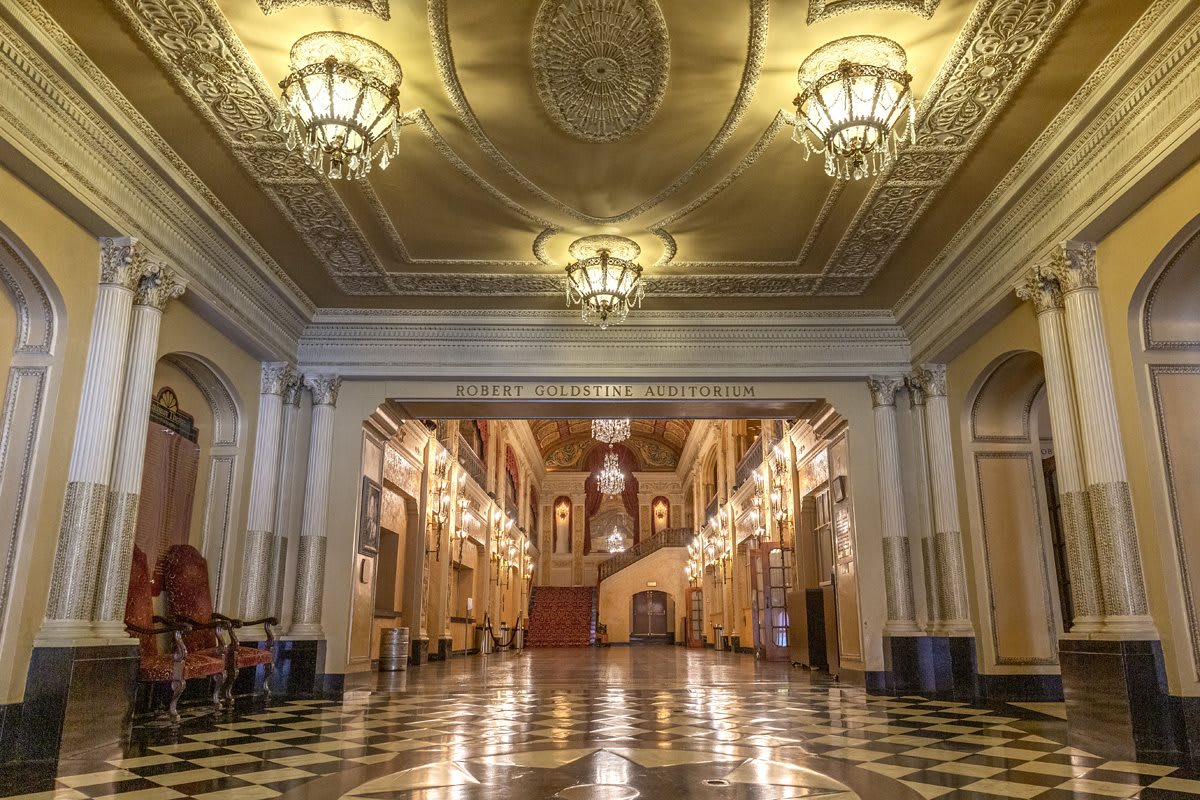 A grand and ornate interior with chandeliers and a marble floor, showcasing historic architecture.