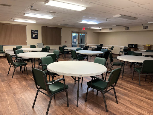A spacious community room set up with round tables and chairs, ready for an event or gathering.