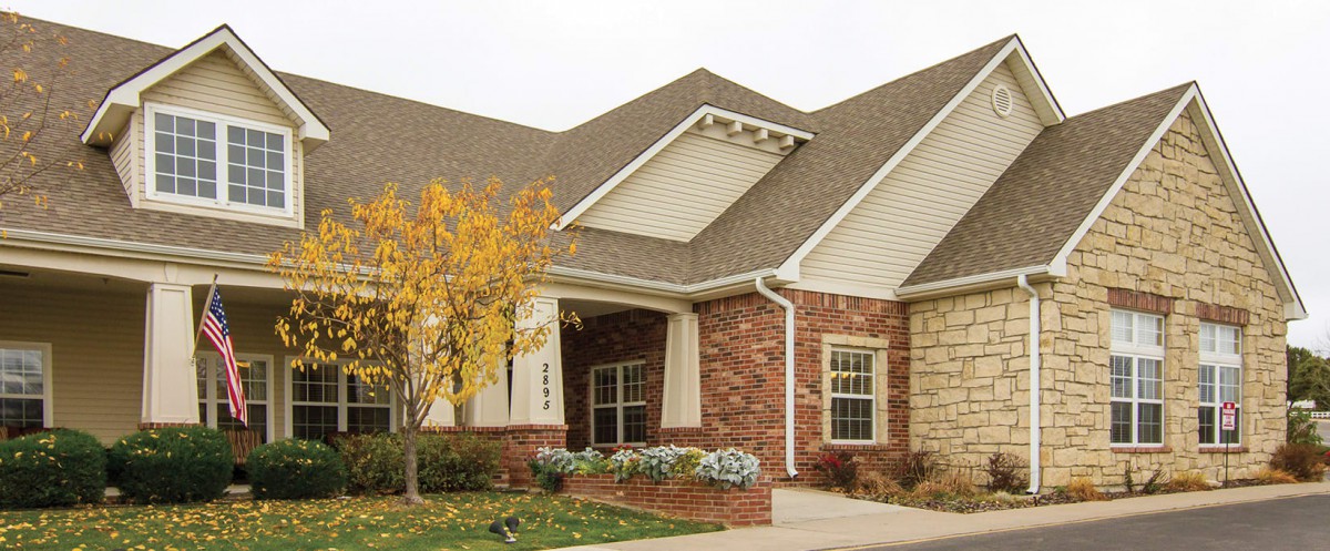 A suburban brick house with a tree in autumn.
