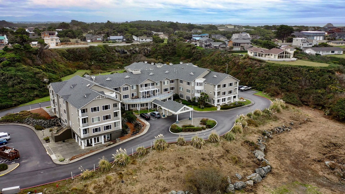 Aerial view of a hotel surrounded by lush greenery and residential buildings.