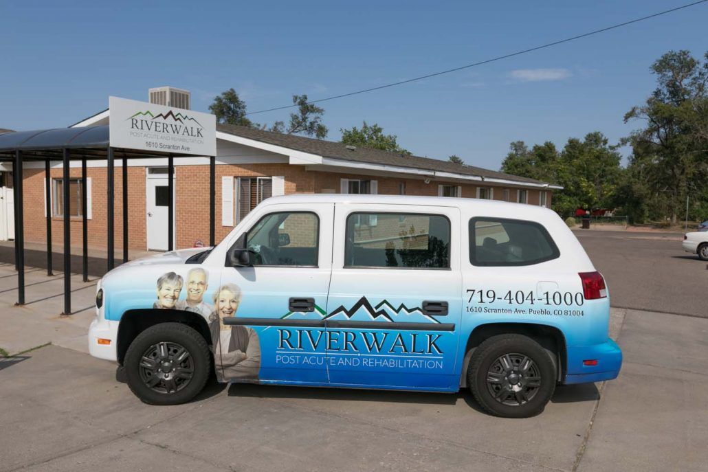 A parked van with business advertising on its side in front of a building.