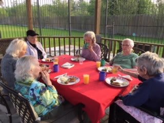 A group of elderly people enjoying a meal together outdoors on a patio.