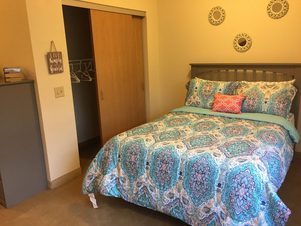 A cozy bedroom with a patterned comforter and decorative wall accents.