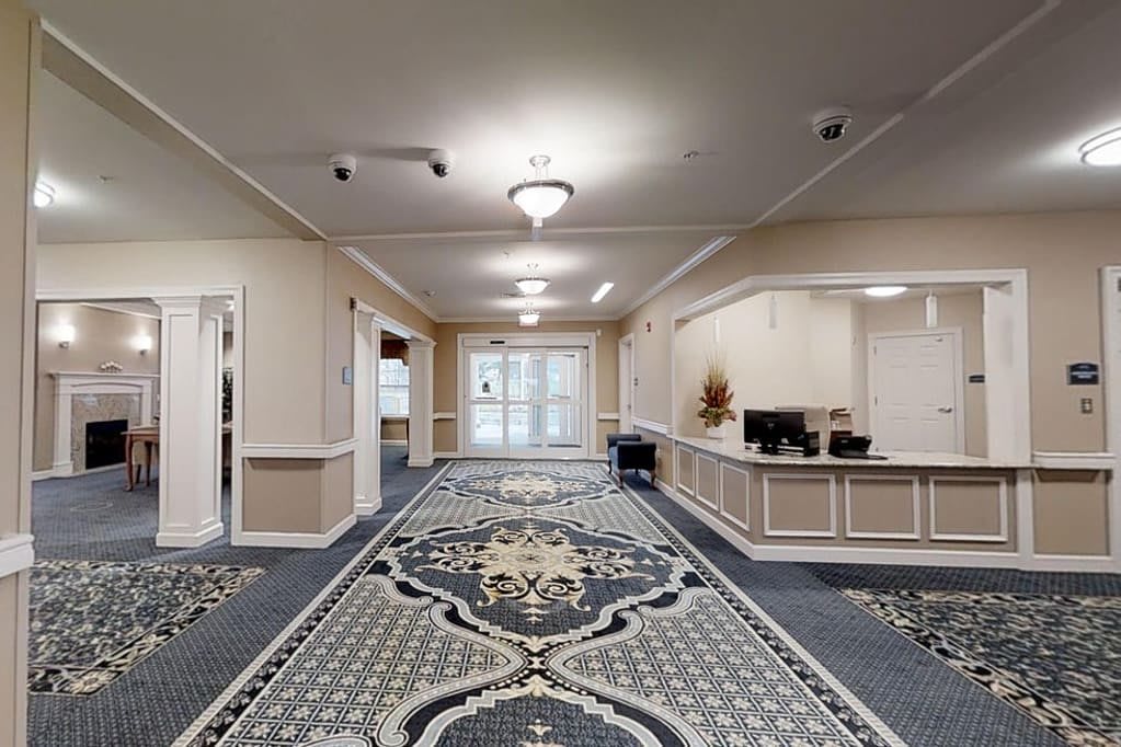 A spacious and elegantly decorated lobby area featuring a reception desk and patterned carpeting.
