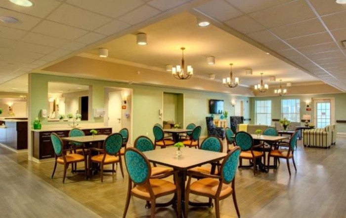 A modern dining area with elegantly arranged tables and chairs, featuring chandeliers for ambient lighting.