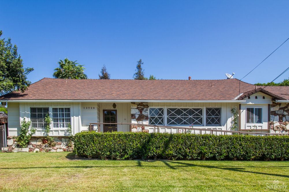 A single-story house with a well-maintained front yard and clear blue sky.
