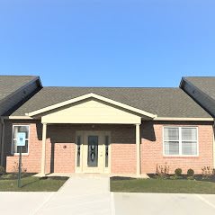 A single-story brick residential building with a central entrance under a clear blue sky.