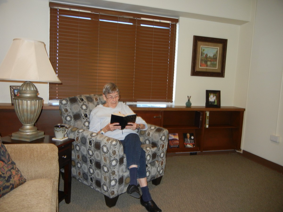 A person sitting comfortably in an armchair, reading a book in a cozy room.