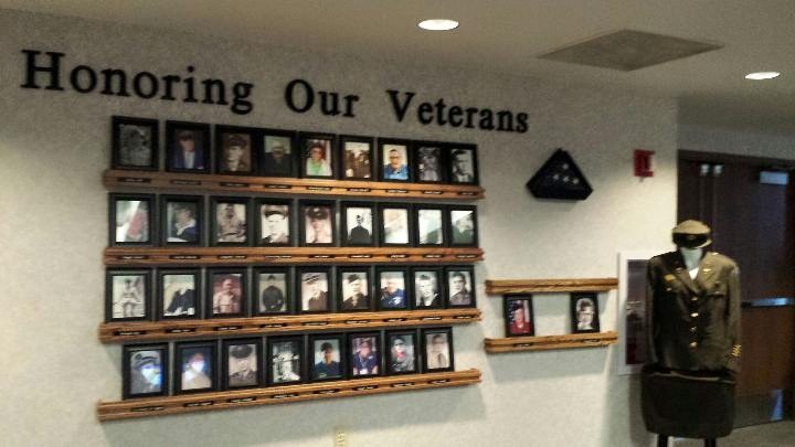 A wall display honoring veterans with framed photos and memorabilia.