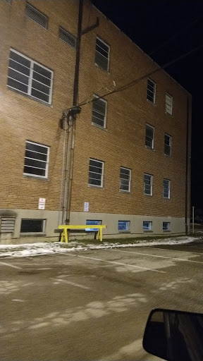 An exterior view of a brick building at night, showcasing its windows and surrounding parking lot.